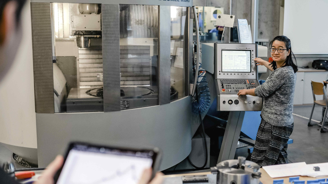 [Translate to English:] zwei Personen im Labor vor einer Fräsmaschine