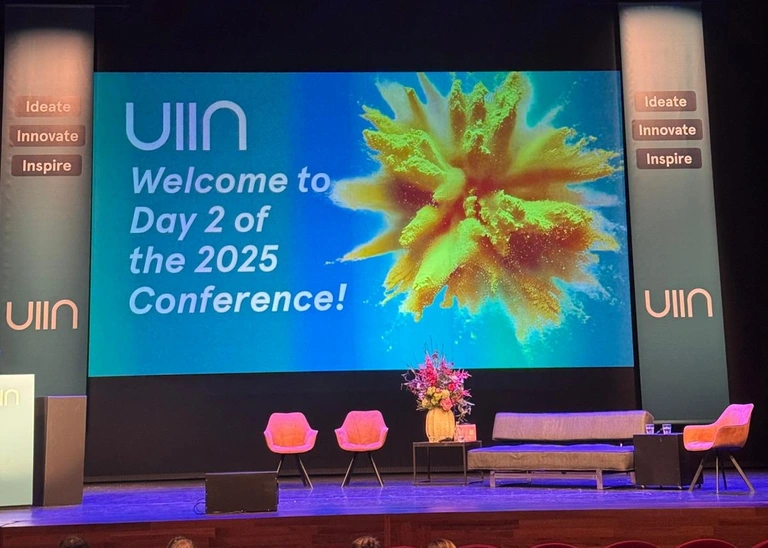 Quelle: THI Foto der Bühne mit der Präsentation im Hintergrund auf der steht: UIIN Welcome to Day 2 of the 2025 Conference!