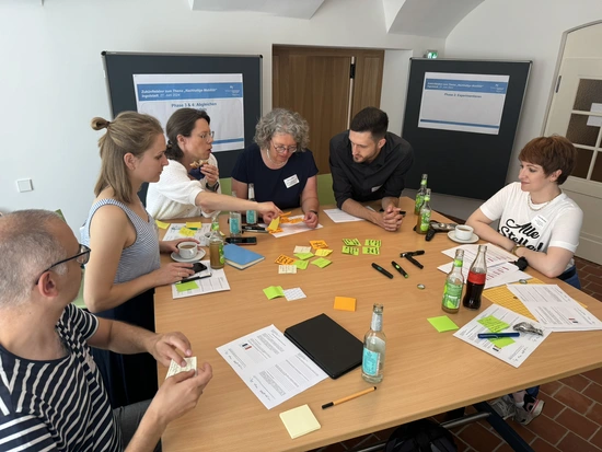 Gruppe von Teilnehmern bei einer Workshop-Session, die an einem Tisch zusammenarbeiten