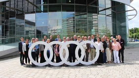 Ein Gruppenfoto am großen Audizeichen am Audiforum Ingolstadt. 