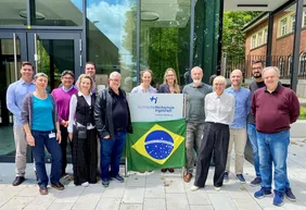 International vernetzt: Der Nachhaltigkeits-Campus Neuburg pflegt einen regen Austausch mit Institutionen aus der ganzen Welt (Foto: THI). Gruppenbild der Gastfamilien am Campus in Neuburg mit einer Brasilien-Flagge