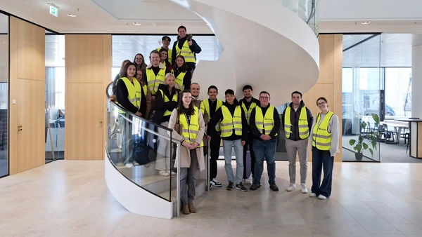 Group photo on a spiral staircase, all wearing yellow safety vests.